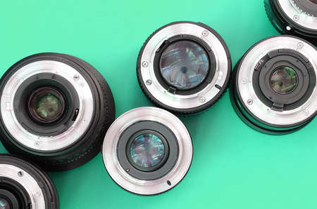 Several photographic lenses lie on a bright turquoise background. Space for textの写真素材