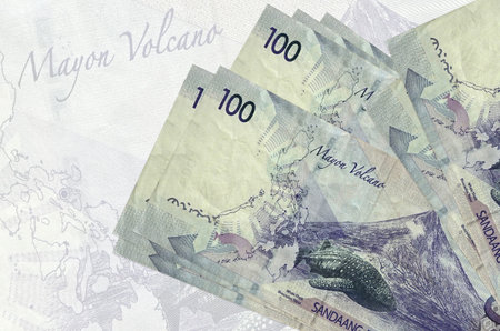 100 Philippine piso bills lies in stack on background of big semi-transparent banknote. Abstract...