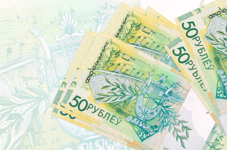 50 Belorussian rubles bills lies in stack on background of big semi-transparent banknote. Abstract...