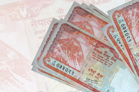 20 Nepalese rupees bills lies in stack on background of big semi-transparent banknote. Abstract presentation of national currency. Business conceptの写真素材