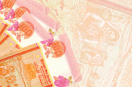 100 Sri Lankan rupees bills lies in stack on background of big semi-transparent banknote. Abstract...
