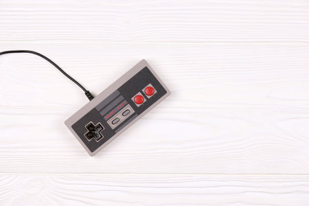KHARKOV, UKRAINE - DECEMBER 27, 2020: Old gamepad for 8-bit video game console nintendo entertainment system and nes mini on white wooden table. Old school retro gamingのeditorial素材