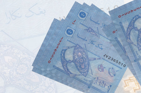 1 Malaysian ringgit bills lies in stack on background of big semi-transparent banknote. Abstract...