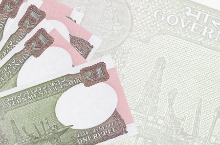 1 Indian rupee bills lies in stack on background of big semi-transparent banknote. Abstract business...