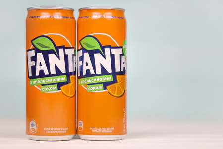 KHARKOV, UKRAINE - DECEMBER 8, 2020: Aluminum cans of Fanta soft drink on white wooden table. Fanta...