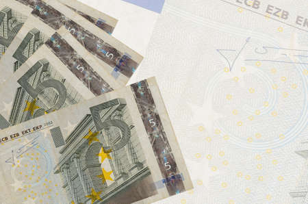 5 euro bills lies in stack on background of big semi-transparent banknote. Abstract business...