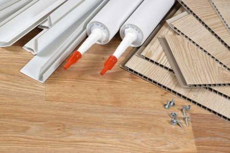 Set of items for PVC ceiling indoor works. Assembly adhesive bottles and PVC panels with plastic...