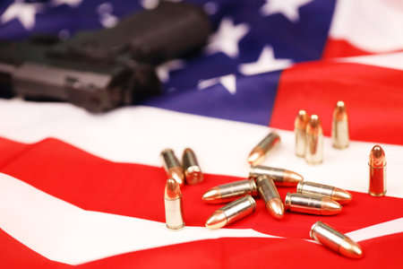 Many yellow 9mm bullets and gun on United States flag. Concept of gun trafficking on USA territory or US shooting rangeの写真素材