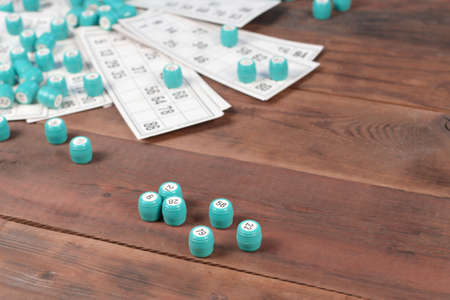 Many barrels with numbers and cards for lotto or russian bingo table game on wooden surface. Russian lotto has similar rules to classical worldwide bingo gameの写真素材