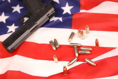 Many yellow 9mm bullets and gun on United States flag. Concept of gun trafficking on USA territory...