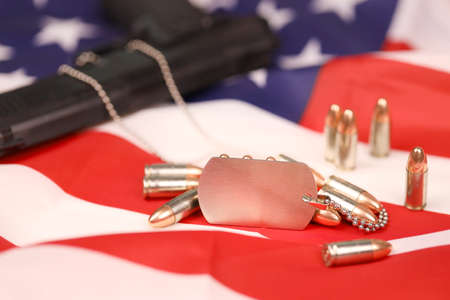Many yellow 9mm bullets and gun with dogtags on United States flag. Concept of duty and service in US army forces. Veteran conceptの写真素材