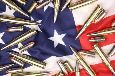Many yellow 9mm and 5.56mm bullets and cartridges on United States flag. Concept of gun trafficking on USA territory or special operationsの写真素材
