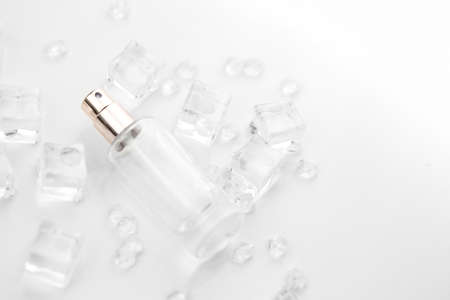 Female perfume bottle, objective photograph of perfume bottle in ice cubes and water. view from above. product photo, concept of freshness and aromaの写真素材