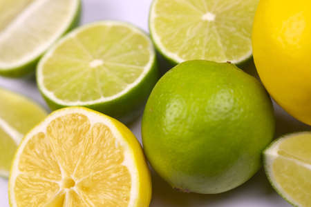 Many halves and slices of yellow lemon and green lime on light white table. Fresh fruits on kitchen topの写真素材