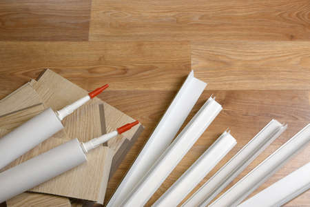 Set of items for PVC ceiling indoor works. Assembly adhesive bottles and PVC panels with plastic corners. Indoor VPC siding kit. Interior renovation works or construction materialsの写真素材