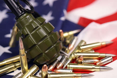 F1 frag grenade and many yellow bullets and cartridges on United States flag. Concept of gun...