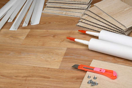 Set of items for PVC ceiling indoor works. Assembly adhesive bottles and PVC panels with plastic corners. Indoor VPC siding kit. Interior renovation works or construction materialsの写真素材