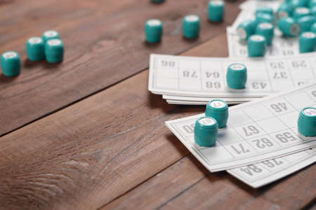 Many barrels with numbers and cards for lotto or russian bingo table game on wooden surface. Russian lotto has similar rules to classical worldwide bingo gameの写真素材