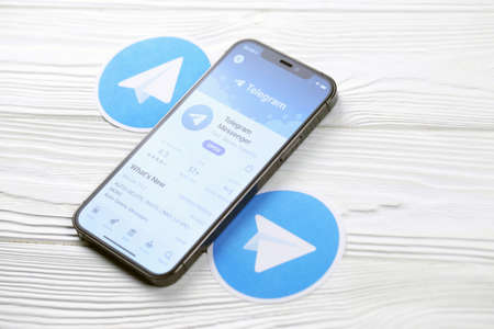 KHARKOV, UKRAINE - MARCH 5, 2021: Telegram Messenger icon and application from App store on iPhone 12 pro display screen on white wooden tableのeditorial素材