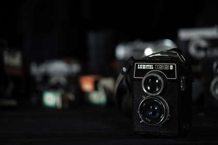 KHARKOV, UKRAINE - APRIL 27, 2021: Lubitel 166b and 2 Film photo camera and another old retro photo equipment on black wooden table in photographer darkroom. Photographic gear from soviet union timesのeditorial素材