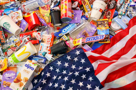 KHARKOV, UKRAINE - AUGUST 10, 2021: US flag on big pile of various wrappings and empty disposable...