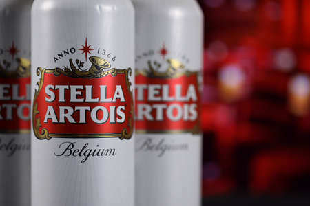 KHARKOV, UKRAINE - FEBRUARY 14, 2021: Stella Artois beer cans on wooden table with red bar interior on background. alcohol productionのeditorial素材
