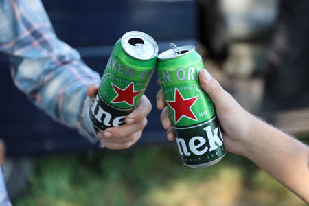 KHARKOV, UKRAINE - JULY 31, 2021: Green tin cans of Heineken pale lager beer in men hands outdoorsのeditorial素材