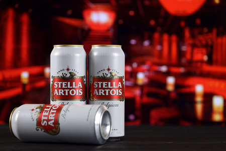 KHARKOV, UKRAINE - FEBRUARY 14, 2021: Stella Artois beer cans on wooden table with red bar interior on background. alcohol productionのeditorial素材