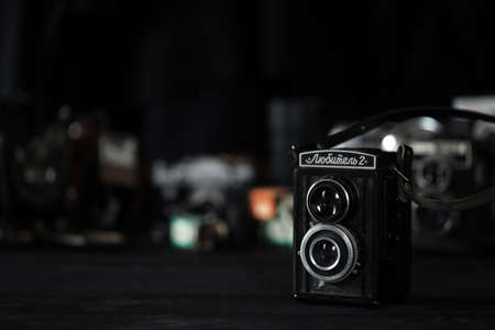 KHARKOV, UKRAINE - APRIL 27, 2021: Lubitel 166b and 2 Film photo camera and another old retro photo equipment on black wooden table in photographer darkroom. Photographic gear from soviet union timesのeditorial素材