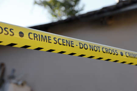 Crime scene tape for covering the area cordon. Yellow tape with blurred forensic law enforcement background in cinematic tone and copy spaceの写真素材