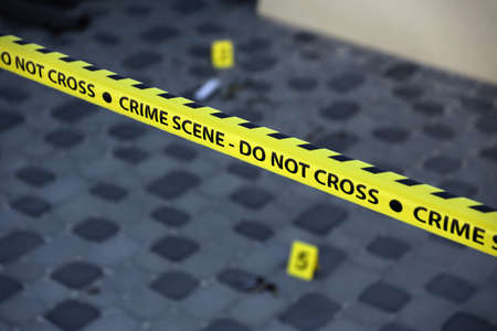 Crime scene tape for covering the area cordon. Yellow tape with blurred forensic law enforcement background in cinematic tone and copy spaceの写真素材