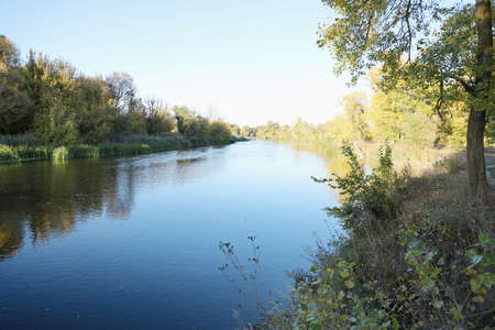 Beautiful autumn landscape with lake and multicoloral trees. Picturesque place with lake and tall...