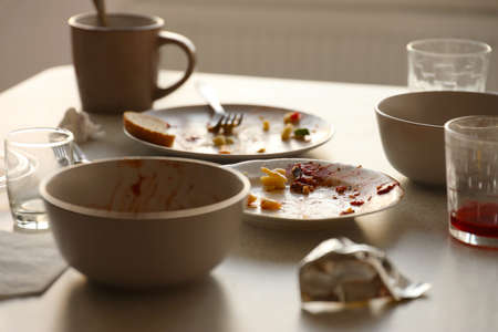 Empty dirty plates with spoons and forks on the table after meal. Banquet ending concept. Unwashed dishes ready to cleanの写真素材