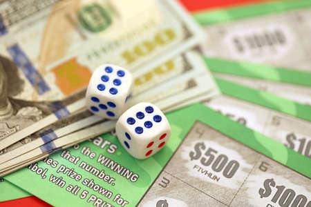 Close up view of green lottery scratch cards with us dollar bills and dice. Many used fake instant lottery tickets with gambling resultsの写真素材