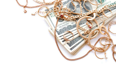 Many expensive golden jewerly rings, earrings and necklaces with big amount of US dollar bills on white background. Pawnshop or jewelery shop conceptの写真素材