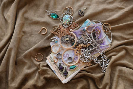 Bunch of stolen jewelry and money on military uniform cloth fabric. Looting by Russian soldiers in the Ukrainian cities during the Russian attack on Ukraine. Marauders and looters conceptの写真素材