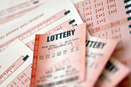 Red lottery ticket lies on pink gambling sheets with numbers for marking to play lottery. Lottery...