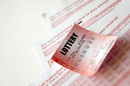 Red lottery ticket lies on pink gambling sheets with numbers for marking to play lottery. Lottery playing concept or gambling addiction. close up photoの写真素材