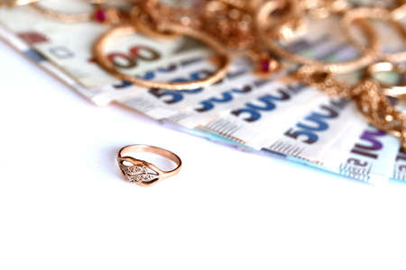 Many expensive golden jewerly rings, earrings and necklaces with big amount of Ukrainian money bills. Pawnshop or jewelery shop. Jewelry trading in Ukraineの写真素材
