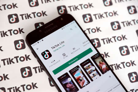 TERNOPIL, UKRAINE - MAY 2, 2022: Tik Tok smartphone app on screen and Many TikTok printed on paper. Tiktok or Douyin is a famous Chinese short-form video hosting service owned by ByteDance Ltdのeditorial素材