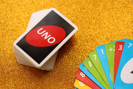 TERNOPIL, UKRAINE - MAY 15, 2022: Many colorful UNO game cards on golden background close up. UNO is an American shedding-type card game that is played with a specially printed deckのeditorial素材
