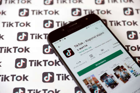 TERNOPIL, UKRAINE - MAY 2, 2022: Tik Tok smartphone app on screen and Many TikTok logo printed on...