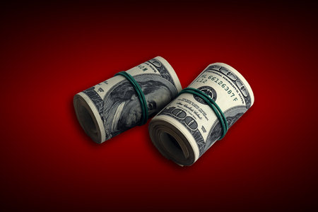 Bundle of US dollar bills on crimson red background. Pack of american money with high resolution on dark red background with dark vignetteの写真素材