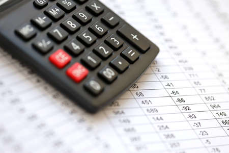 Big black calculator lies on financial statement and balance sheet on desk of auditor close up....