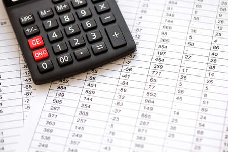Big black calculator lies on financial statement and balance sheet on desk of auditor close up....