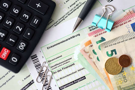 German income tax return form with pen and european euro money bills lies on accountant table close...