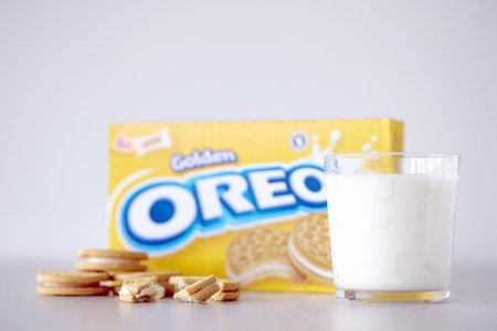 TERNOPIL, UKRAINE - MAY 28, 2022: Oreo golden crispy cookies with glass of milk on white background. The brand Oreo is owned by american company Mondelez internationalのeditorial素材