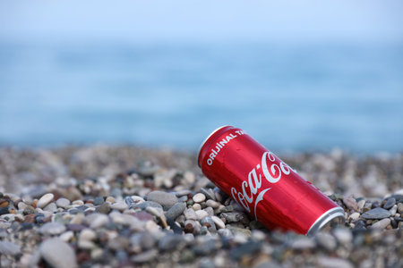 ANTALYA, TURKEY - MAY 18, 2021: Original Coca Cola red tin can lies on small round pebble stones close to sea shore. Coca-cola on turkish beach stonesのeditorial素材