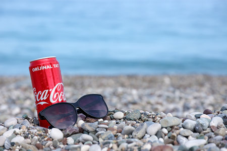ANTALYA, TURKEY - MAY 18, 2021: Original Coca Cola red tin can lies on small round pebble stones...