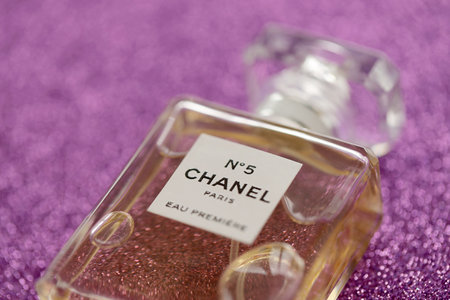 TERNOPIL, UKRAINE - SEPTEMBER 2, 2022 Chanel Number 5 Eau Premiere famous worldwide french perfume bottle on shiny glitter background in pink and purple colorsのeditorial素材